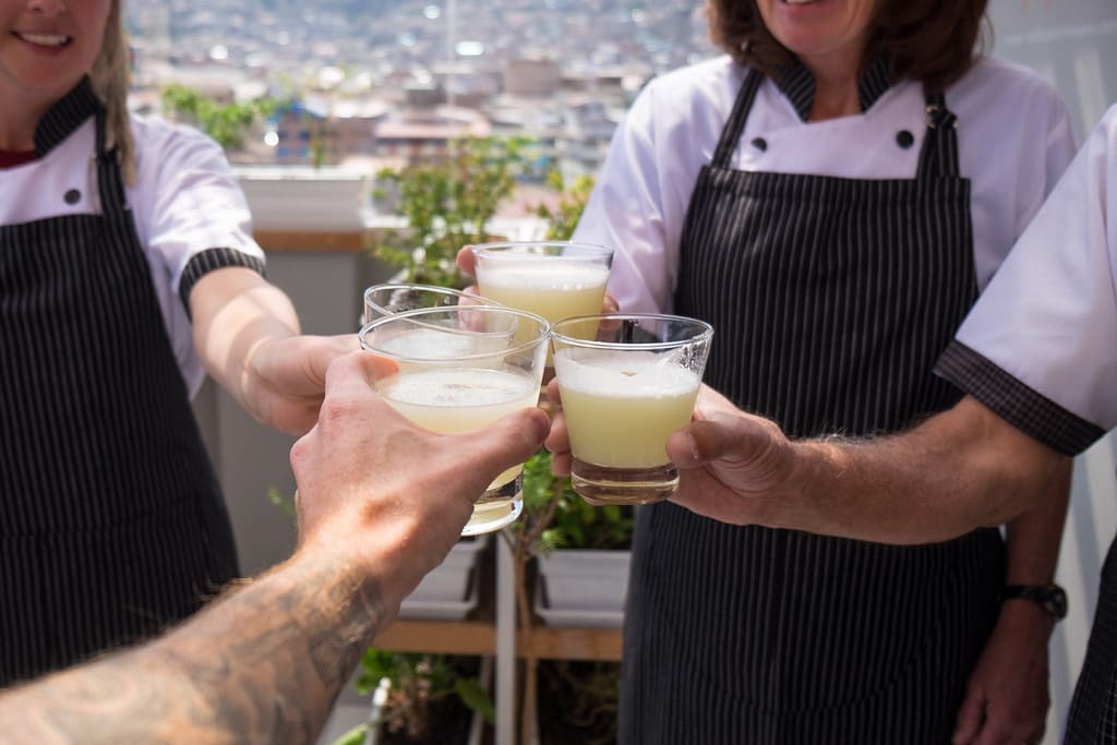 Cooking class in Cusco - Four hands making a toast with pisco.