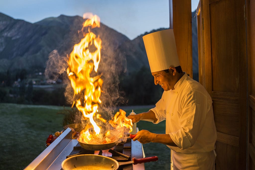 Luxury hotels in Sacred Valley - Chef with flaming pan during cooking classes at Inkaterra Hacienda.